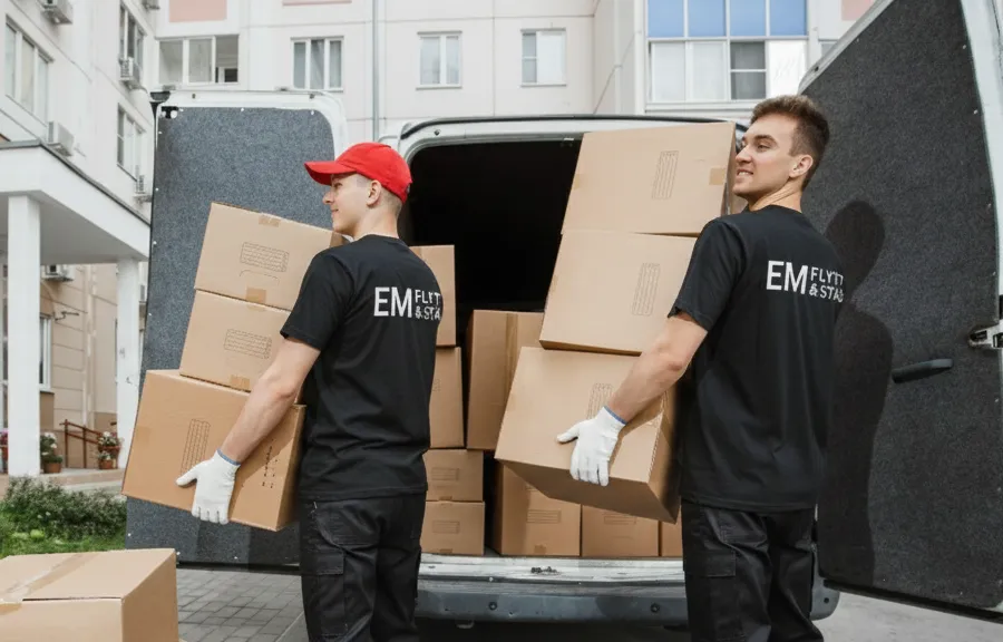 Flyttpersonal lastar kartonger i flyttbil